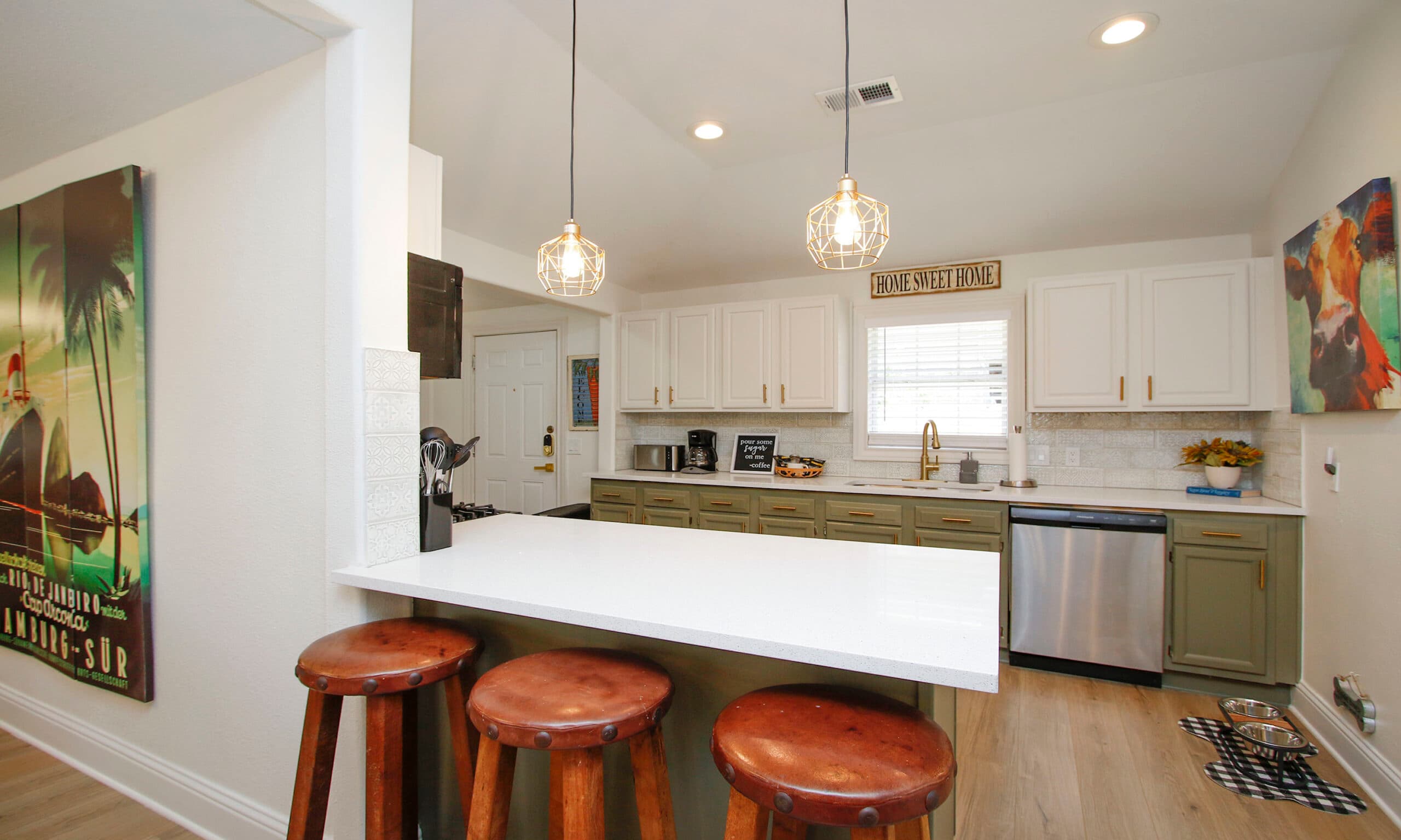 Kitchen with breakfast bar, leather stools, and pendant lights