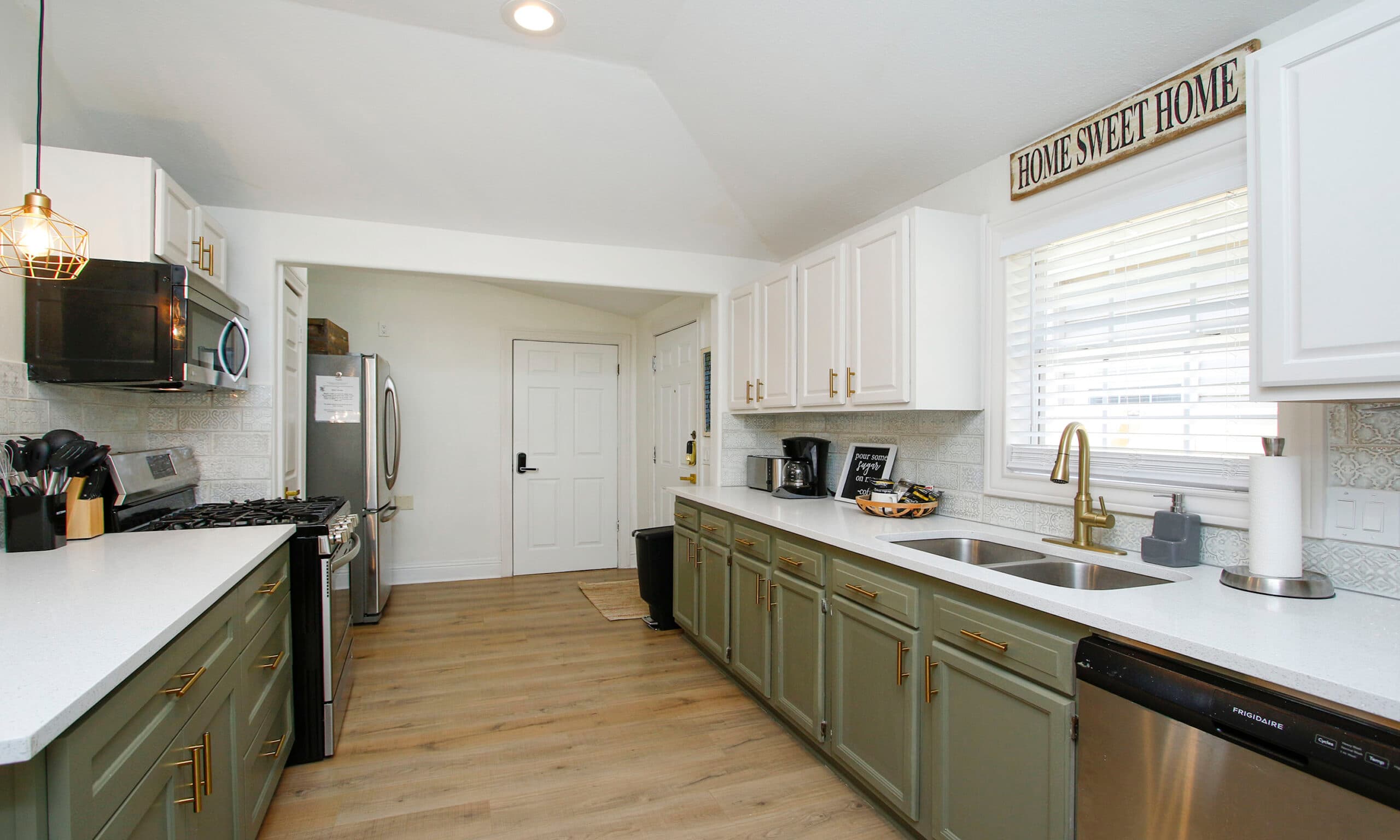 Full kitchen galley with sage green cabinets and stainless appliances