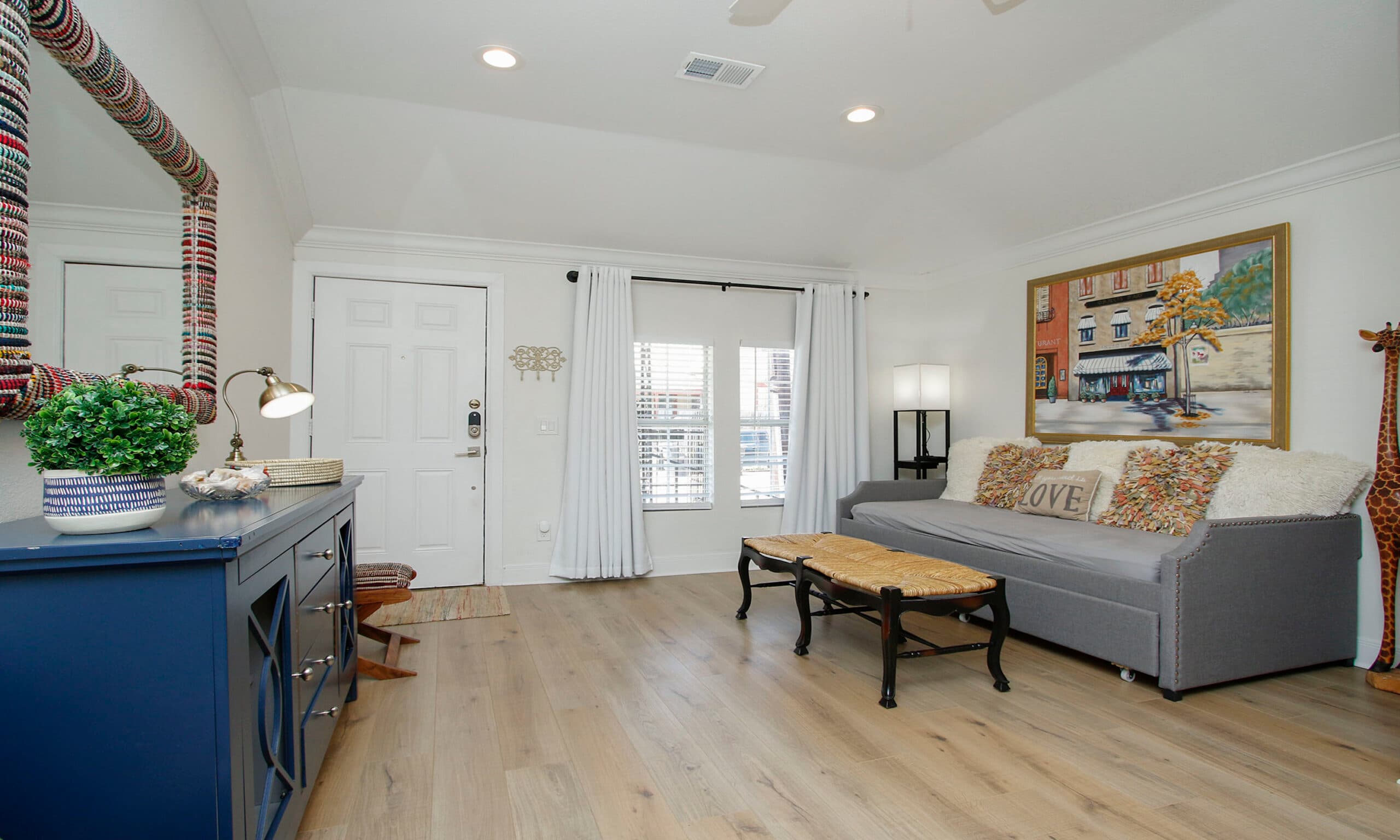 Living room entry with front door, curtains, and cozy furnishings