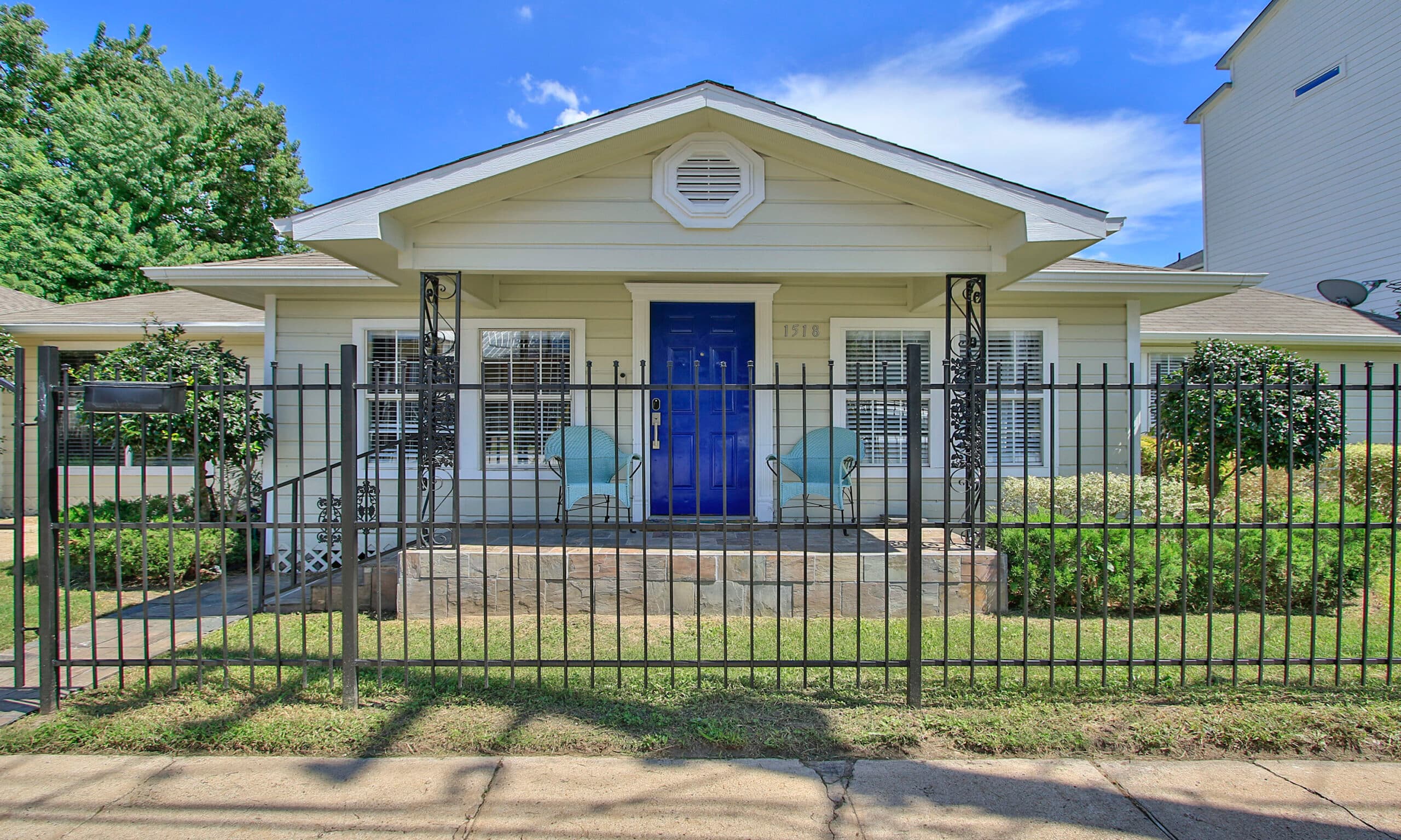 Front view of the Sawyer Yards Art Depot bungalow at 1518 Sabine St, with iron fence and blue door
